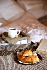 Wooden tray with light breakfast on bed