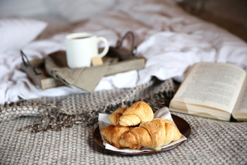Wooden tray with light breakfast on bed