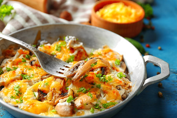 Roasted mushrooms, chicken and cheese gratin in pan, on color wooden background
