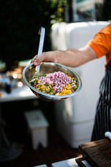 Cook preparing salad in a tin bowl