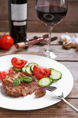 Roasted beef fillet and fresh vegetables on plate, on wooden background