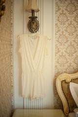 Cream dress hangs on a hanger in the night light in the room