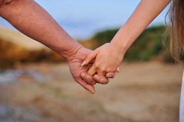 Young people are a pair of lovers in the sand and hold hands