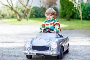 Fototapeta premium Little preschool boy driving big toy old vintage car, outdoors