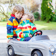 Two happy sibling boys playing with big old toy car 