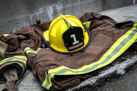 Firefighter uniform with yellow helmet on a concrete step.