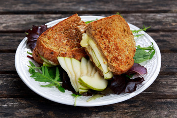 Rustic homemade bread grilled into sandwich with Pear and cheese on old wooden table