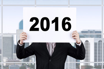 Worker covering his face with number 2016 on the board