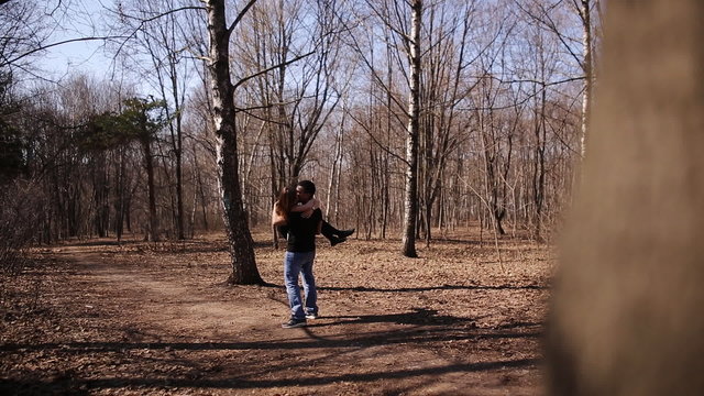 man turns a girl on his hands in the spring forest park