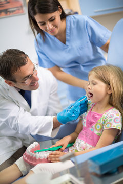 Dentist views teeth to young girl in dental chair