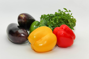Разноцветные перцы и баклажаны на белом фоне.