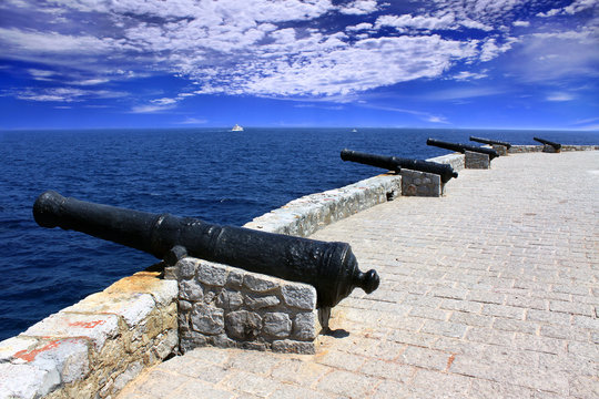 Fototapeta Row of old cannons aiming at the sea on the fortress, Hydra island, Greece