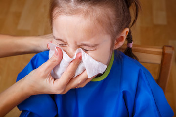 Parent hand helping the playing little girl to blow her nose with a hygienic wet wipe. Seasonal...