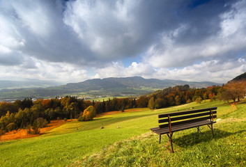 Panoramic sunny autumn alpine view with bench