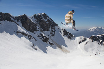 Naklejka na ściany i meble Flying snowboarder on mountains. Extreme sport