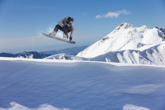 Flying snowboarder on mountains. Extreme sport