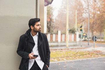 Handsome Indian man texting in an urban context