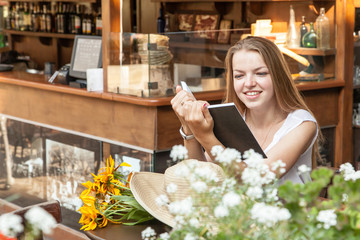 smiling girl sitting at summer terrace and reading book