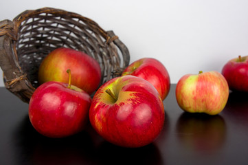 Red apples in basket on black wooden background