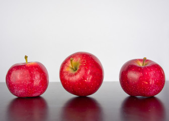three apples on a black background with reflection