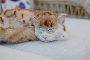 Fototapeta na wymiar Toy Cat lying on a sofa 
