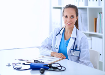 Portrait of young female doctor sitting at desk in hospital