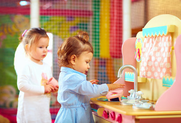 little girls playing at toy kitchen in kindergarten