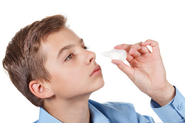 Nasal spray drops in hand of ill young boy, closeup on white