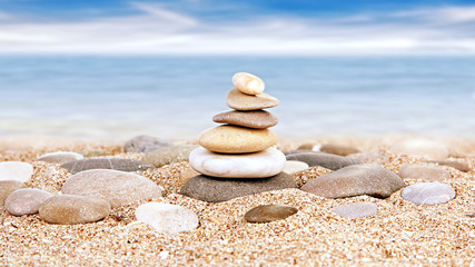 Fototapeta na wymiar Tower of stones on sea beach background