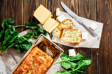 baked cheese pie with spinach , feta and fresh ingredients on a wooden background