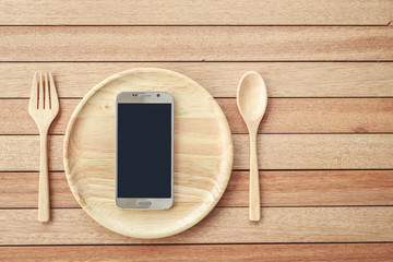 Top view smartphone on wooden dish on wooden plank background