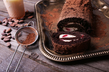 Chocolate roll with cream and berries on table close up