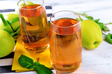 Glasses of apple juice with fruits and fresh mint on table close up