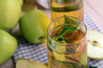 Glasses of apple juice with fruits and fresh mint on table close up