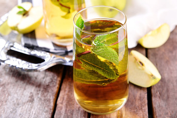 Glasses of apple juice with fruits and fresh mint on table close up