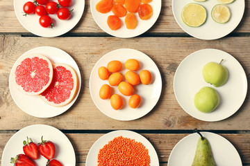 Different products on saucers on wooden table, top view