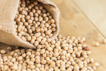 Soy beans in sack on wooden desk