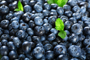 Tasty ripe blueberries with green leaves close up