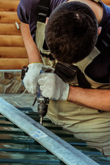 Work screwdriver. Worker fastens screwdriver steel sheet coating to the steel frame.