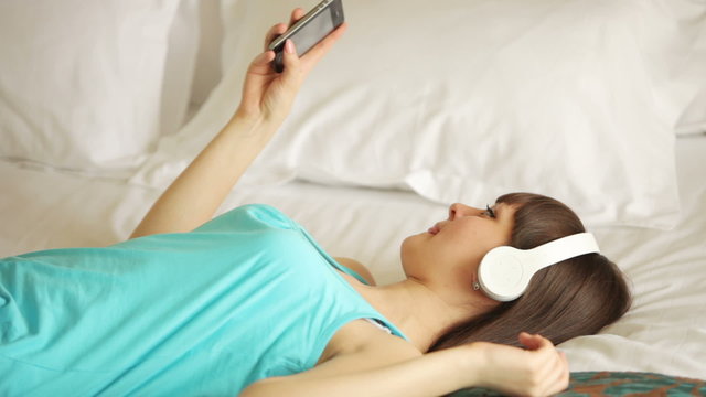 Young woman listening music on bed
