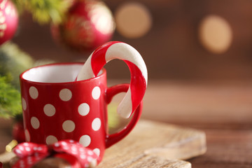 Christmas Candy Canes in cup with Christmas decoration on table on bright background