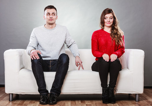 Shy woman and man sitting on sofa