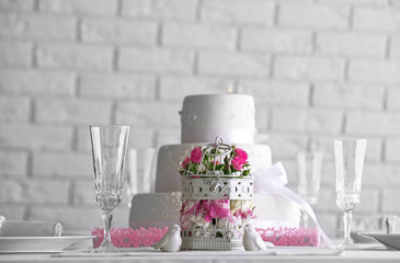 Layered wedding cake and flowers in cage on decorated table