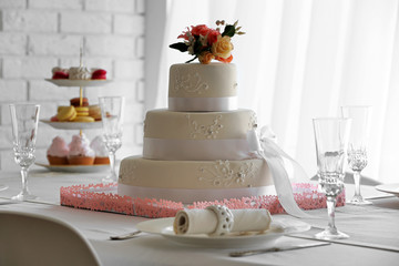 Obraz na płótnie Canvas Wedding layered cake on decorated table in restaurant