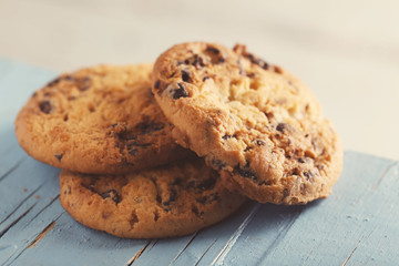Cookies with chocolate crumbs on blue wooden table against blurred background, close up