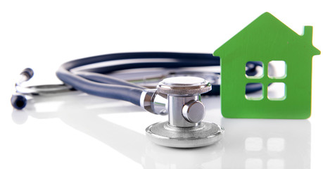 Concept of family medicine - green house and stethoscope isolated on white background