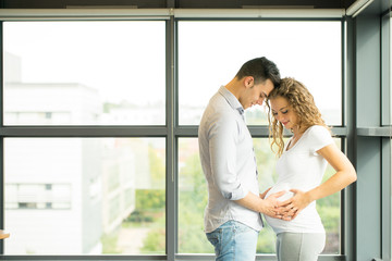 Happy and young pregnant couple in studio, white background