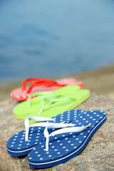 Bright flip-flops on stone, nature background