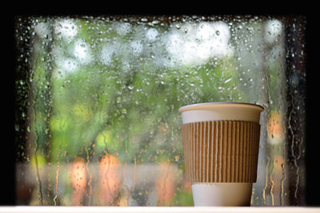 Naklejka na ściany i meble Paper cup of coffee on a rainy day window background