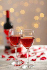Setting of glasses with wine, bottle and a gift in the box, on white blurred background